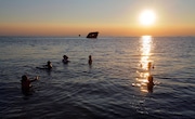 Beachgoers play in the surf just before sunset at Sunset Beach. Seen in the background is the S.S. Atlantus, the remains of an experimental concrete ship that went aground during a storm at this location in June 1926.